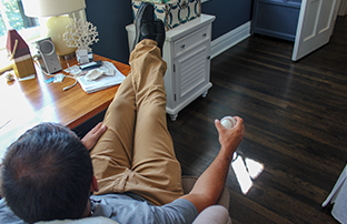 boy sitting with his feet on a desk holding a baseball in his hand with wood flooring in the background