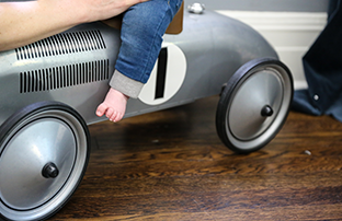 toddler riding a toy on a wood floor