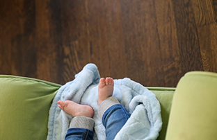 little baby feet on a blanket with wood flooring