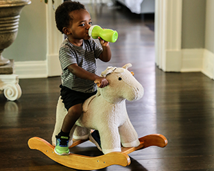 toddler playing on a rocking toy on a wood floor