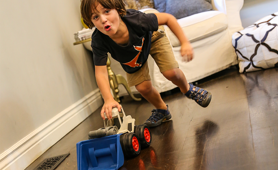 boy playing with a toy truck on a wood floor