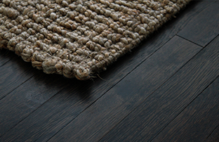 dark wood floor with the corner of a rug over it